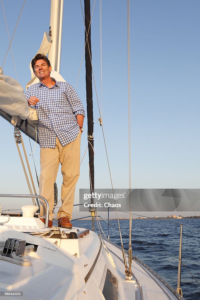 Active man relaxing on deck of sailboat at sunset.