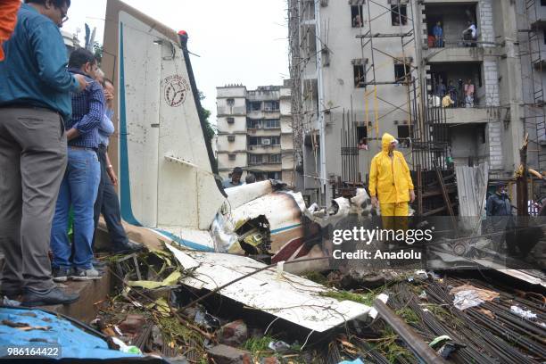 Indian firemen and aviation officials inspect the wreckage of a plane that crashed into a construction site, killing five people, in Mumbai on June...