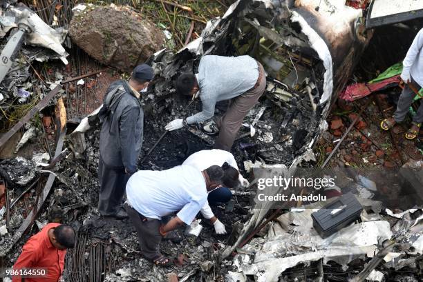 Indian firemen and aviation officials inspect the wreckage of a plane that crashed into a construction site, killing five people, in Mumbai on June...