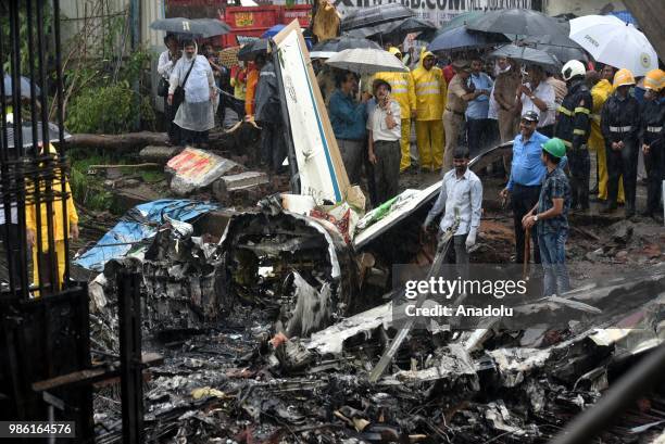 Indian firemen and aviation officials inspect the wreckage of a plane that crashed into a construction site, killing five people, in Mumbai on June...