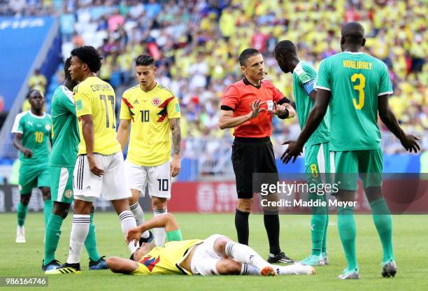 Referee Milorad Mazic speaks with Cheikhou Kouyate of Senegal after he fouls Radamel Falcao of Colombia who goes down injured during the 2018 FIFA...