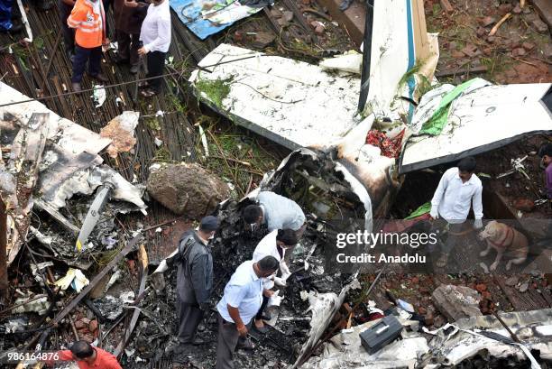 Indian firemen and aviation officials inspect the wreckage of a plane that crashed into a construction site, killing five people, in Mumbai on June...