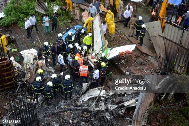 Indian firemen and aviation officials inspect the wreckage of a plane that crashed into a construction site, killing five people, in Mumbai on June...