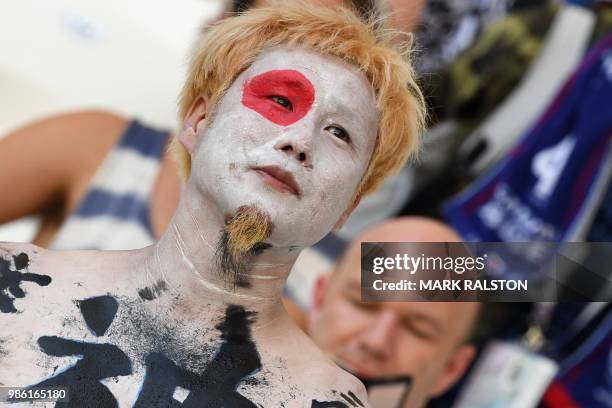 Japan's fan with the national flag painted on his face and ideograms on the chest looks on as he waits before the Russia 2018 World Cup Group H...