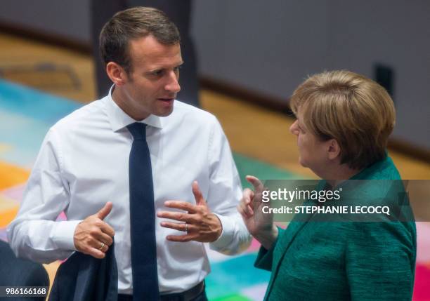 French President Emmanuel Macron speaks with German Chancellor Angela Merkel at the start of an European Union summit focused on migration, Brexit...