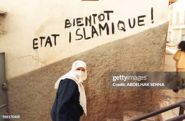 Veiled woman passes by a graffiti reading : "Soon the Islamic state" on a wall of Algiers' Casbah, February 11 1992, one day after the slaying of six...