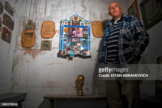 The former director of Argentinos Juniors sports club and owner of the 'Casa de Dios' museum, Alberto Perez, poses next to Argentine football star...