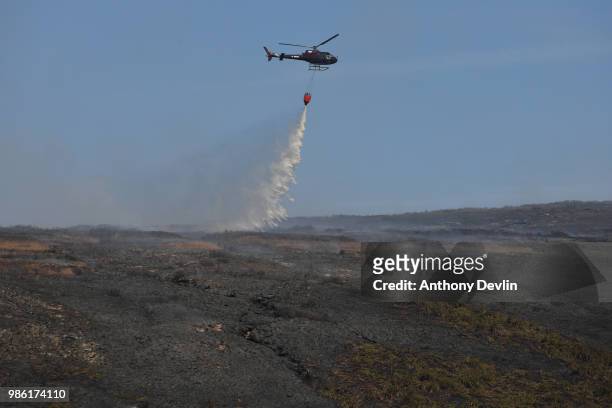 Helicopter drops water on smouldering moorland as wildfires continue to burn on the moors on June 28, 2018 in Stalybridge, England. Around 100...