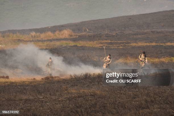 Soldiers douse a wildfire on Saddleworth moor near Stalybridge, northwest England on June 28, 2018. - A hundred soldiers and a military helicopter...