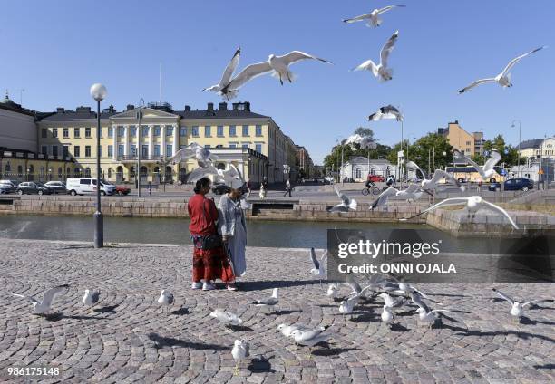 Tourists feed seagulls in front of the Presidential palace in Helsinki, Finland on June 28, 2018. - A long-awaited first summit between US President...