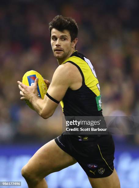 Trent Cotchin of the Tigers runs with the ball during the round 15 AFL match between the Richmond Tigers and the Sydney Swans at Etihad Stadium on...