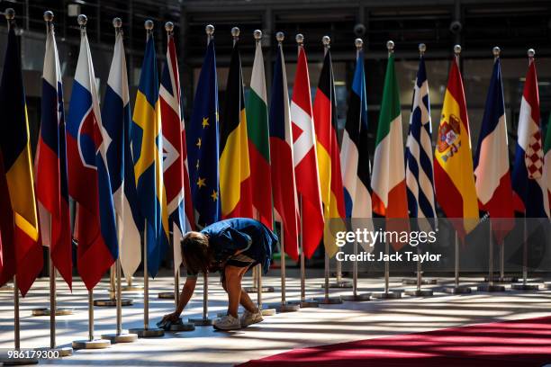 Woman polishes a flag pole at the Council of the European Union on the first day of the European Council leaders' summit on June 28, 2018 in...