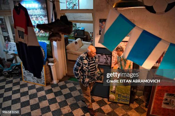 The former director of Argentinos Juniors sports club and owner of the 'Casa de Dios' museum, Alberto Perez, walks past Argentine football star Diego...