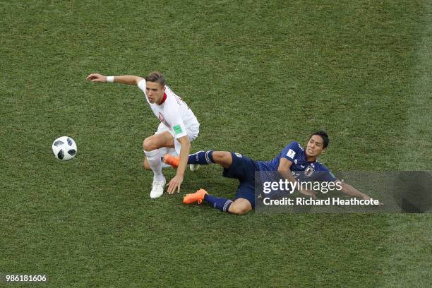 Yoshinori Muto of Japan tackles Jan Bednarek of Poland during the 2018 FIFA World Cup Russia group H match between Japan and Poland at Volgograd...