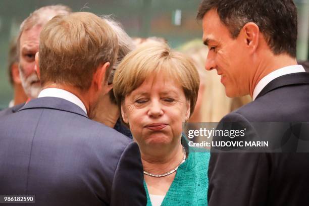 Germany's Chancellor Angela Merkel reacts as she speaks with European Council President Donald Tusk and Spain's Prime Minister Pedro Sanchez during...