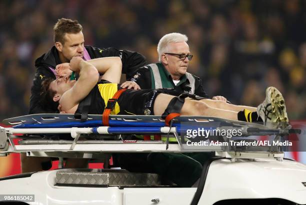 Reece Conca of the Tigers leaves the field with a leg injury in his 100th game during the 2018 AFL round 15 match between the Richmond Tigers and the...