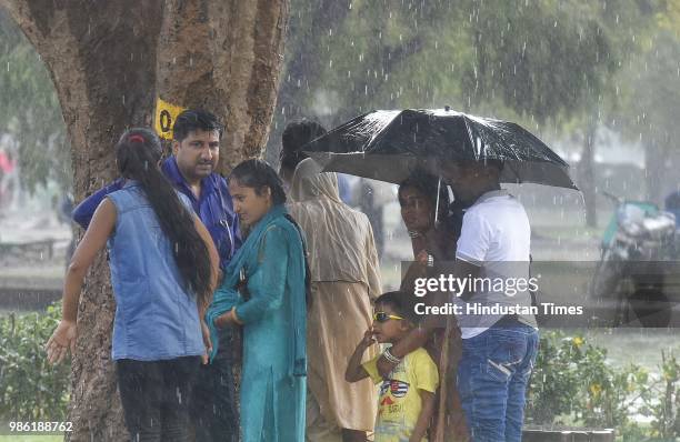 People seen standing under a tree during rain, at India Gate, on June 28, 2018 in New Delhi, India. Delhi and National Capital Regions witnessed the...