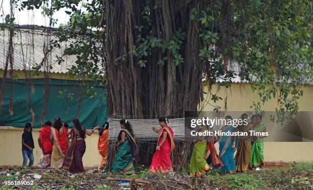 Hindu women tying threads and performing puja around the holy Banyan tree on the occasion of Vat Purnima at Jogeshwari Railway Station, on June 27,...