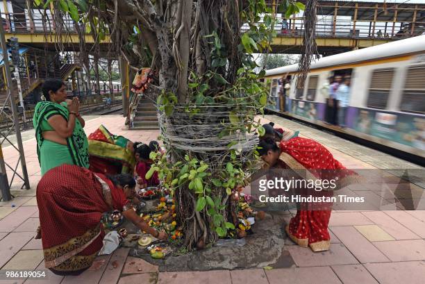 Hindu women tying threads and performing puja around the holy Banyan tree on the occasion of Vat Purnima at Jogeshwari Railway Station, on June 27,...