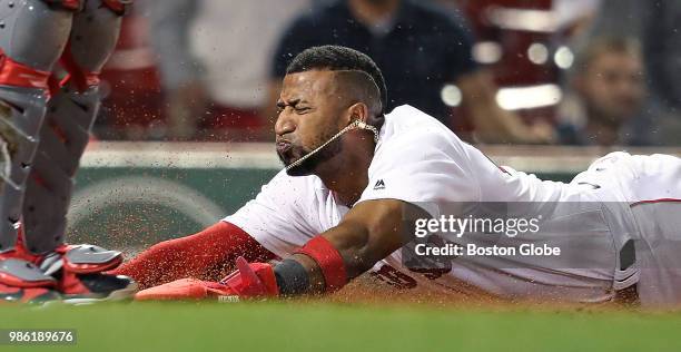 Boston Red Sox player Eduardo Nunez dives safely into home plate, scoring on a bottom of the seventh inning hit by Rafael Devers to put Boston back...