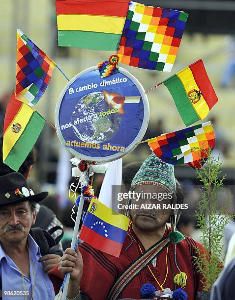 An indigenous Aymara man holds a sign reading "Climate change affects us all, let's act now" with Bolivian, Venezulean and Tahuantinsuyo flags during...