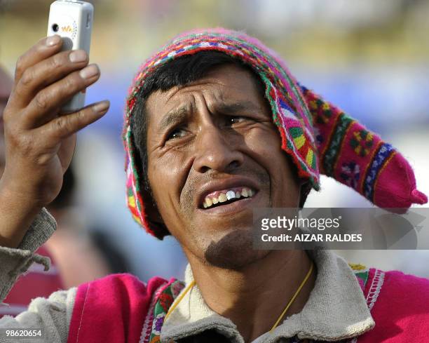 An indigenous Aymara man takes a picture with a mobile phone during a World Climate Change Conference at the Feliz Capriles stadium in Cochabamba,...