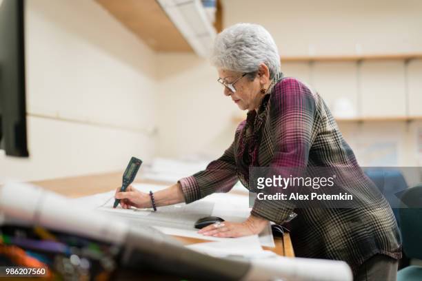 senior silver-haired woman, engineer, using curvimeter when she working with architectural project - alex potemkin or krakozawr stock pictures, royalty-free photos & images