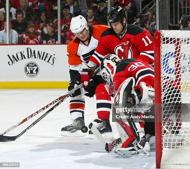 Goaltender Martin Brodeur of the New Jersey Devils makes a stick save as Dean McAmmond of the New Jersey Devils and Arron Asham of the Philadelphia...