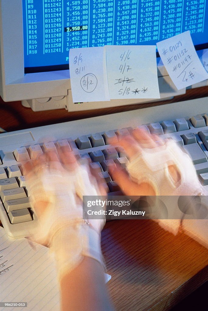 Hands wearing braces, typing at keyboard (carpal tunnel syndrome)