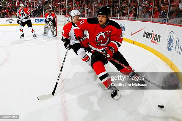 Dean McAmmond of the New Jersey Devils chases the puck along the boards against Kimmo Timonen of the Philadelphia Flyers in Game 5 of the Eastern...
