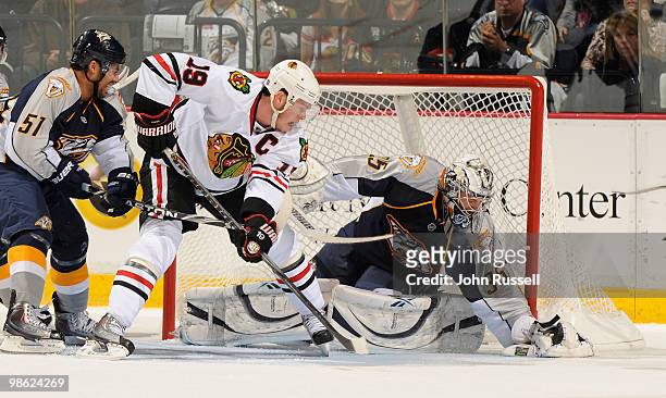 Goalie Pekka Rinne of the Nashville Predators covers the puck in front of teammate Francis Bouillon and Jonathan Toews of the Chicago Blackhawks in...