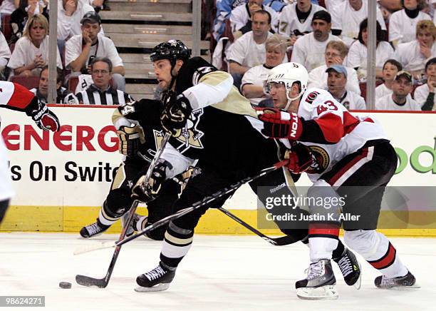 Craig Adams of the Pittsburgh Penguins taks a shot on goal while being defended by Peter Regin of the Ottawa Senators in Game Five of the Eastern...