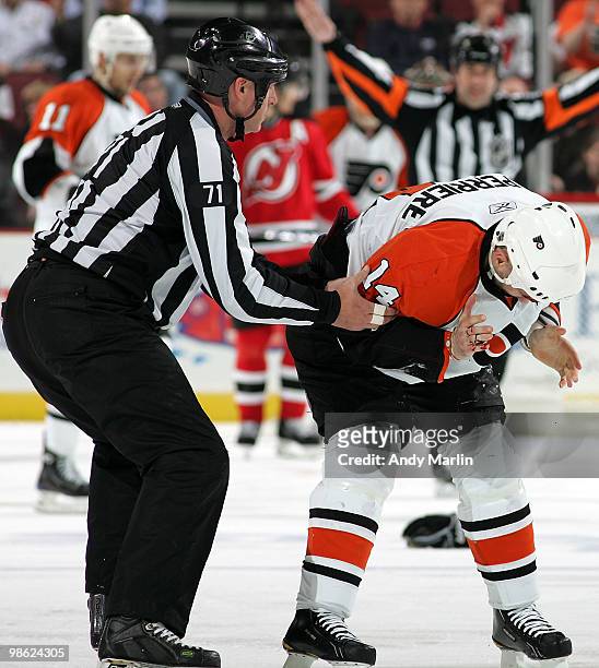 Ian Laperriere of the Philadelphia Flyers is helped by linesman Brad Kovachik after Laperriere was hit in the face by a shot against the New Jersey...