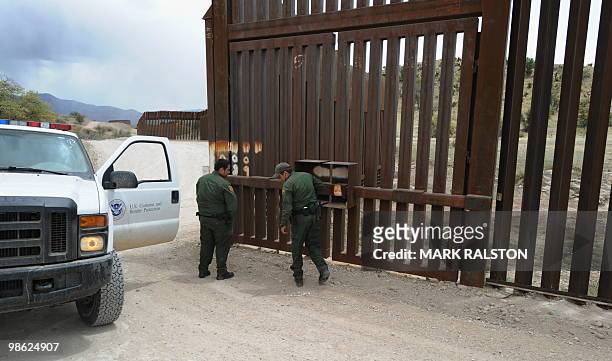 Two US Border Patrol officers stop beside the border fence as they track the path of illegal aliens who have crossed into the US from Mexico near the...