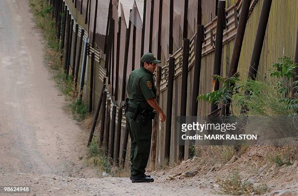 Border Patrol officers walks beside the border fence that divides the US from Mexico in the town of Nogales, Arizona on April 22, 2010. Two...