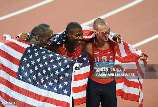 Athletes Lashawn Merritt, Angelo Taylor, David Neville and Jeremy Wariner, wrapped in their national flag, celebrate after winning the men's 4x400m...