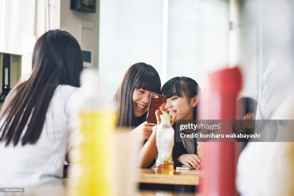 School student watching smartphone at break time
