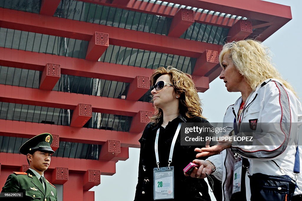 Two women walk past a Chinese soldier st