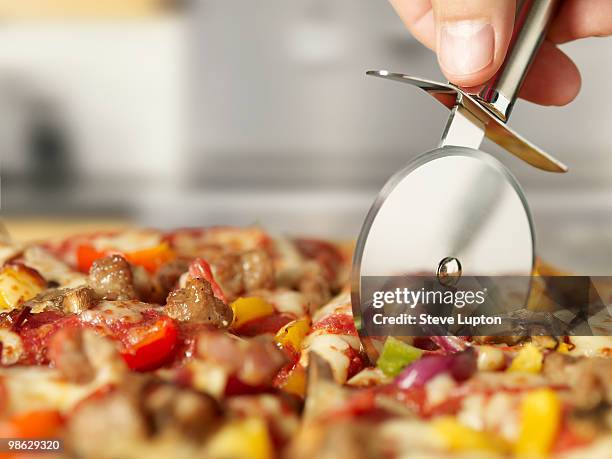 cutting pizza with a pizza wheel - cortador de pizza imagens e fotografias de stock