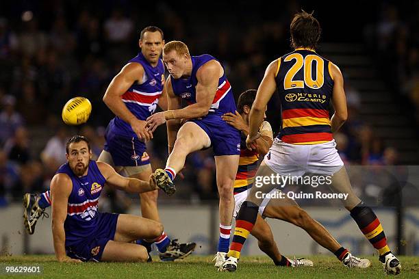 Adam Cooney of the Bulldogs kicks whilst being tackled by Jared Petrenko of the Crows during the round five AFL match between the Western Bulldogs...