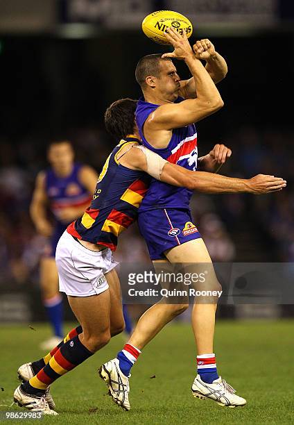 Lindsay Gilbee of the Bulldogs handballs over his head whilst being tackled by Ricky Henderson of the Crows during the round five AFL match between...
