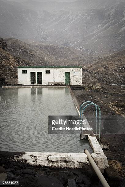 Popular tourist attraction for mountain climbers, Seljavallalaug, a swimming pool in a valley in the Eyjafjoll mountain range is covered by a thick...
