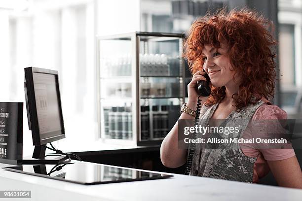 woman answering phone at reception of salon - salon reception stock-fotos und bilder
