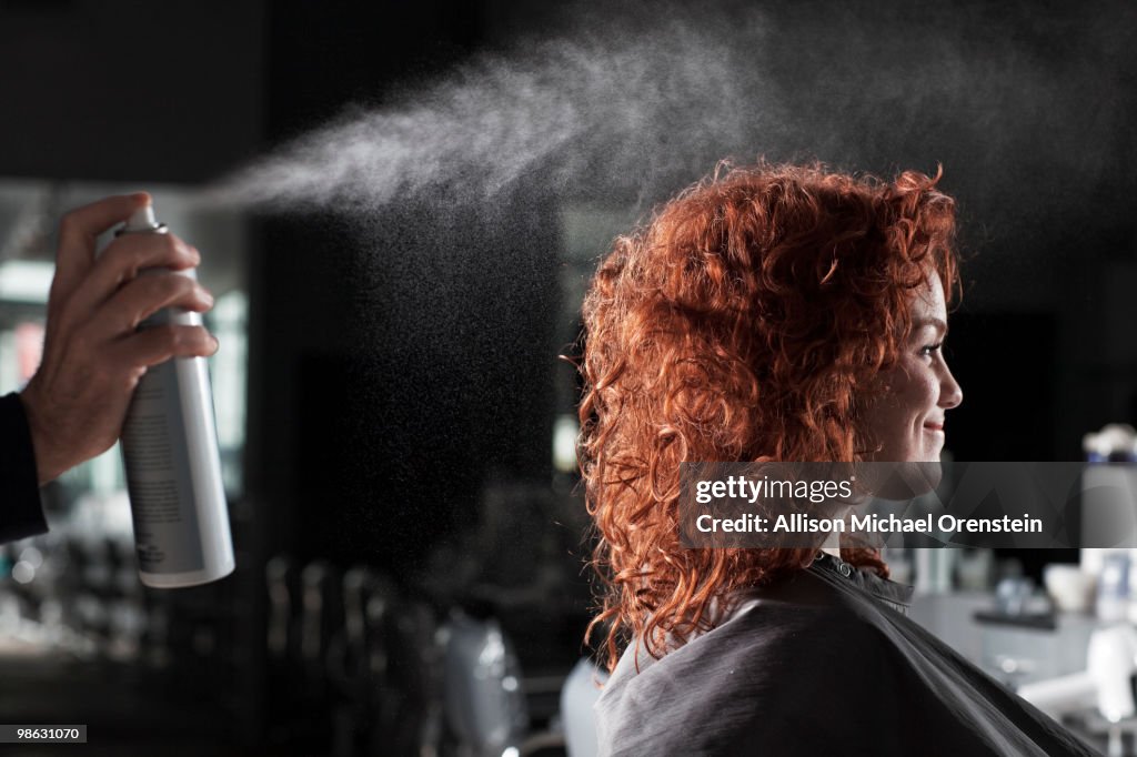 Woman getting hair sprayed at salon