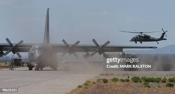 United States Air Force HH-60 Pave Hawk helicopter lands beside a C-130 plane after conducting a rescue operation during Exercise Angel Thunder, near...