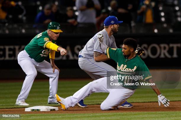 Marcus Semien of the Oakland Athletics slides into third base for a triple ahead of a tag from Mike Moustakas of the Kansas City Royals in front of...