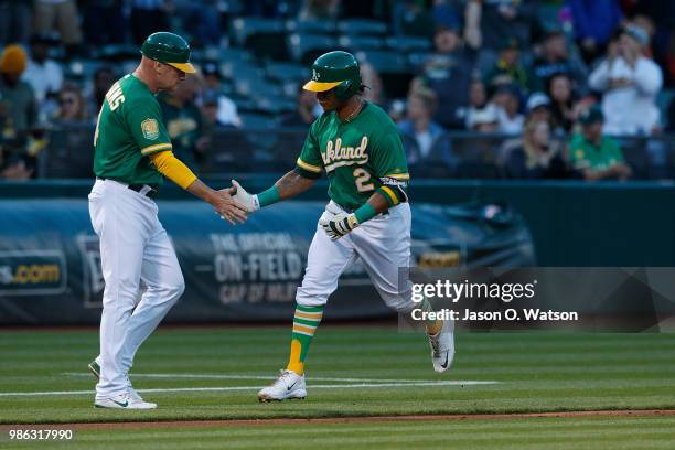 Khris Davis of the Oakland Athletics is congratulated by third base coach Matt Williams after hitting a home run against the Kansas City Royals...