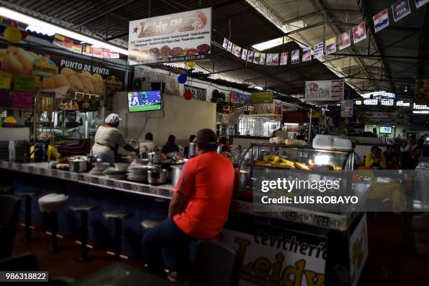 People watch the World Cup match between Colombia and Senegal on TV at a popular market in Cali, Colombia, on June 28, 2018. - Colombia beat Senegal...