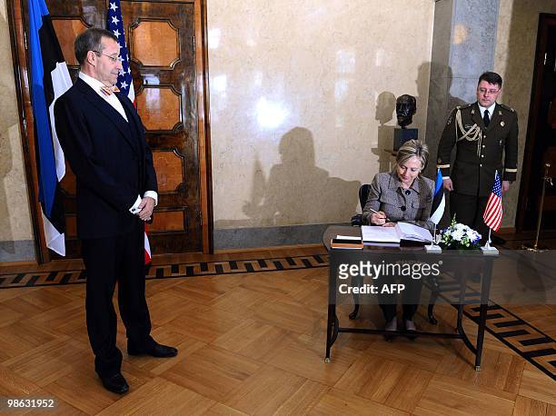 Estonia's President Toomas Hendrik Ilves looks at US Secretary of State Hillary Clinton preparing to sign a guest book after the North Atlantic...