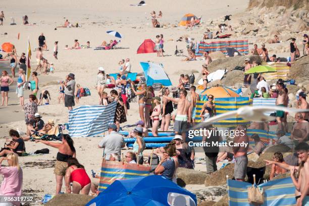 People enjoy the fine weather as they spend time on the beach at Sennen Cove near Penzance on June 28, 2018 in Cornwall, England. Parts of the UK are...